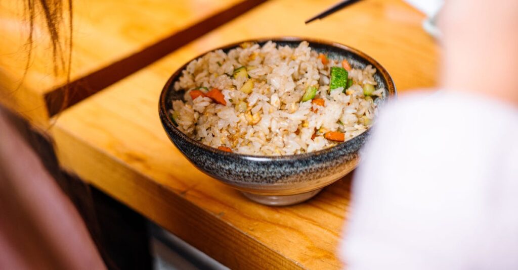 キャンプ場でご飯メニューを食べる子どもたちと両親。焼きおにぎりやカレーチャーハンがテーブルに並ぶ風景。