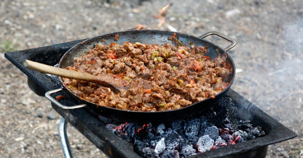 キャンプ場で使われる鋳鉄製のダッチオーブン鍋の写真。焚き火の上で加熱されている様子がリアルに伝わる。