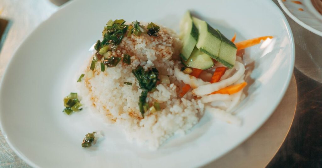キャンプ場でご飯メニューを食べる子どもたちと両親。焼きおにぎりやカレーチャーハンがテーブルに並ぶ風景。