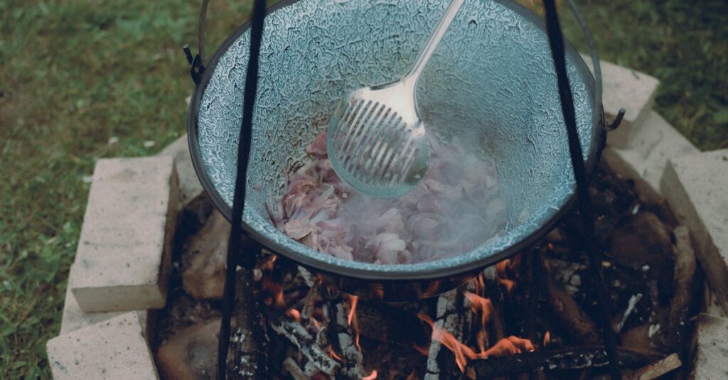 キャンプ場で使われる鋳鉄製のダッチオーブン鍋の写真。焚き火の上で加熱されている様子がリアルに伝わる。