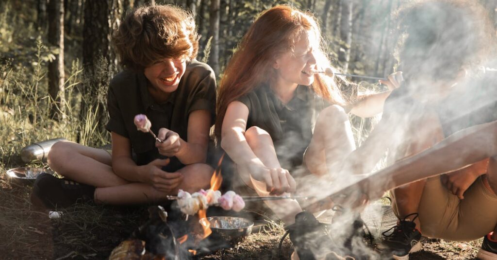 キャンプ場で子どもたちが冷やしうどんや焼きそばドッグを笑顔で食べている様子。トッピングバイキングも楽しげな雰囲気。
