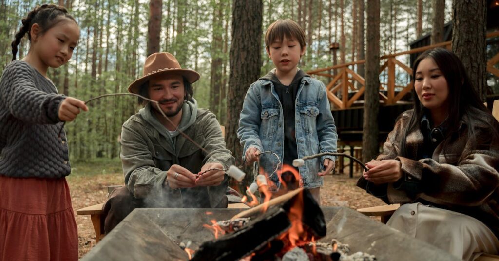キャンプ場で家族が昼食を囲んで笑顔で過ごす風景。テーブルに並ぶ彩り豊かな料理と子どもたちの楽しそうな表情が印象的。