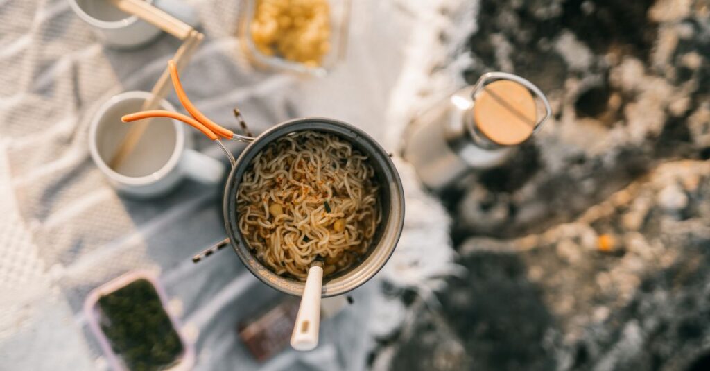 キャンプの昼食準備に必要な調理道具や食材が並ぶ、整理されたチェックリスト風のイメージ。