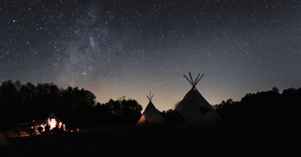 星空の下で焚き火を囲みながら過ごす秋キャンプの幻想的な様子を写した写真