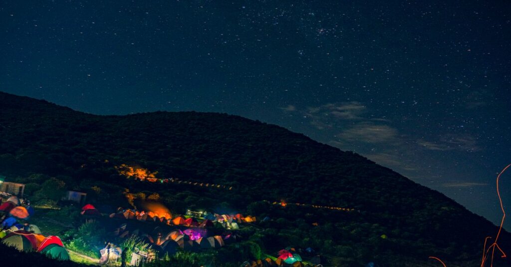 星空の下で焚き火を囲みながら過ごす秋キャンプの幻想的な様子を写した写真