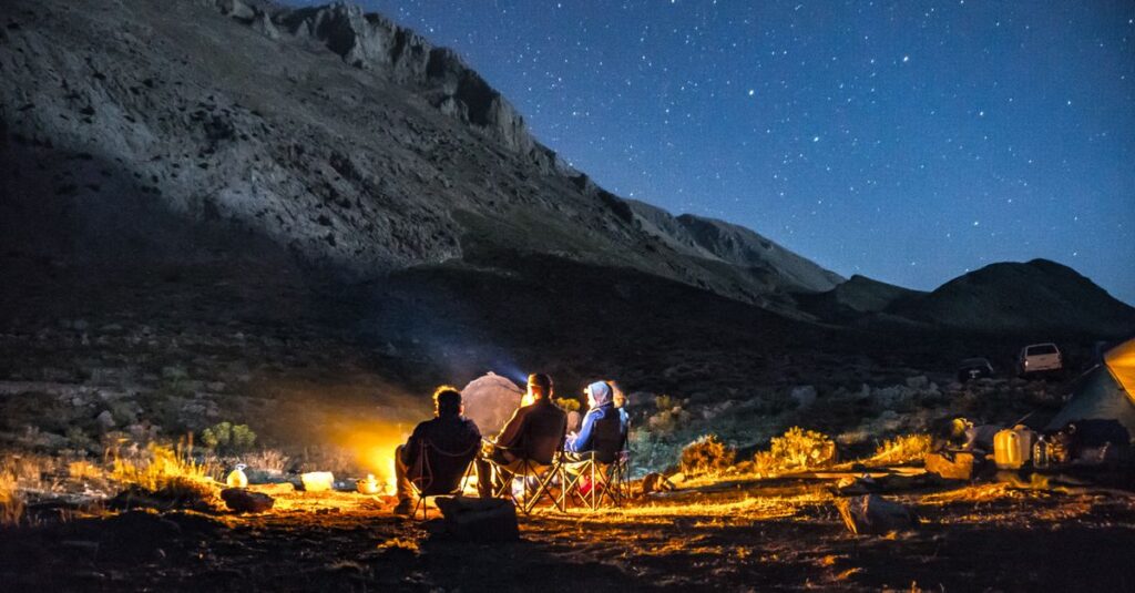 星空の下で焚き火を囲みながら過ごす秋キャンプの幻想的な様子を写した写真